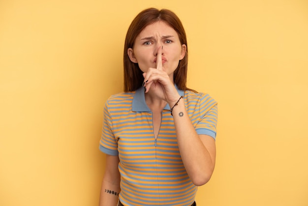 Young English woman isolated on yellow background keeping a secret or asking for silence