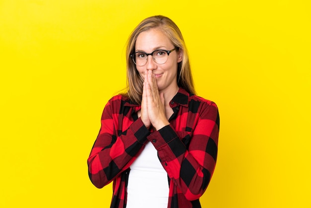 Young English woman isolated on yellow background keeps palm together. Person asks for something