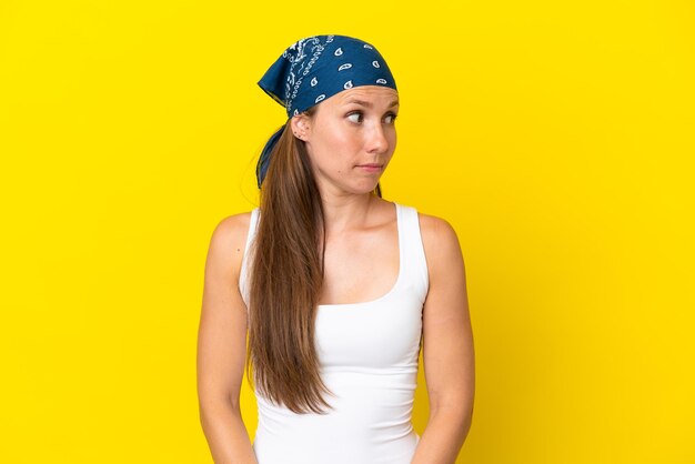 Photo young english woman isolated on yellow background making doubts gesture looking side