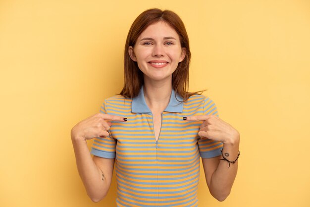 Young English woman isolated on yellow background person pointing by hand to a shirt copy space proud and confident