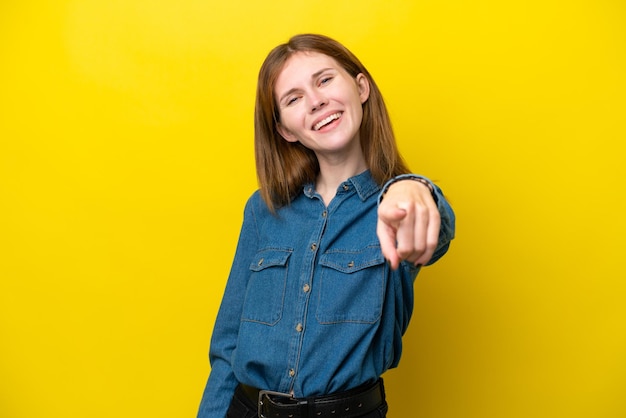 Young English woman isolated on yellow background pointing front with happy expression