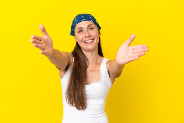 Young english woman isolated on yellow background presenting and inviting to come with hand