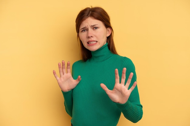 Young English woman isolated on yellow background rejecting someone showing a gesture of disgust.