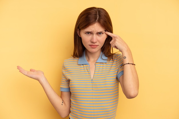 Young English woman isolated on yellow background showing a disappointment gesture with forefinger.