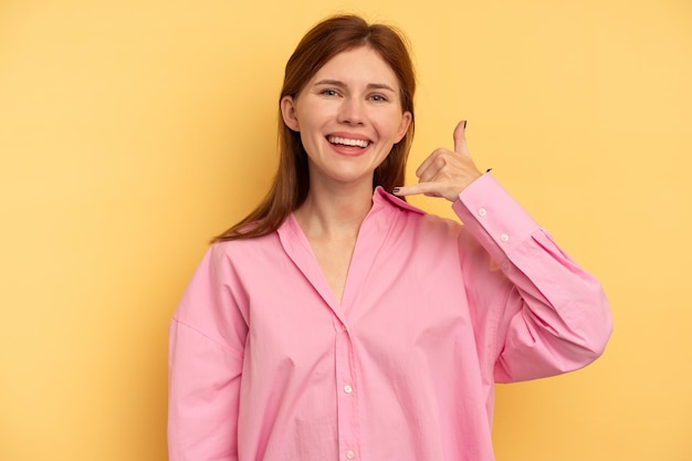 Young English woman isolated on yellow background showing a mobile phone call gesture with fingers.