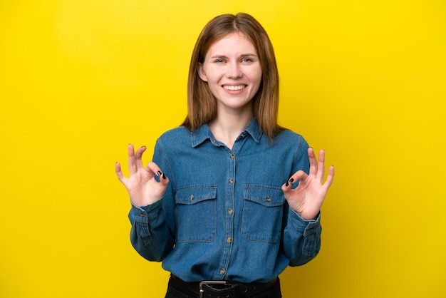 Young English woman isolated on yellow background showing ok sign with two hands