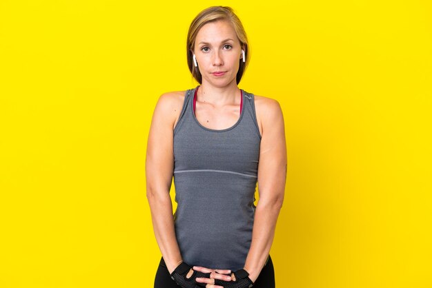 Young English woman isolated on yellow background stretching arm