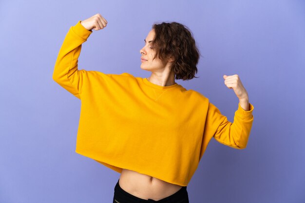 Young English woman on purple doing strong gesture