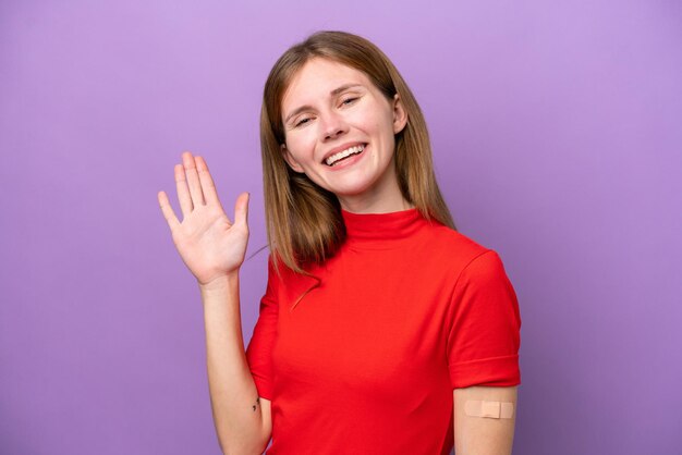 Young English woman wearing bandaids isolated on purple background saluting with hand with happy expression