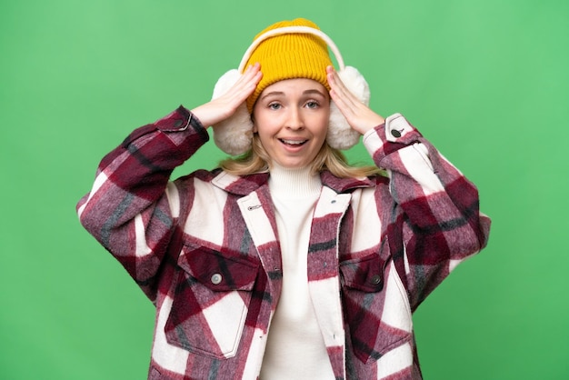 Young English woman wearing winter muffs over isolated background with surprise expression