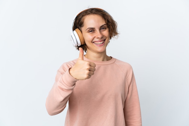 Young English woman on white listening music and with thumb up