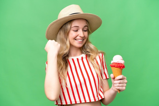 Young english woman with a cornet ice cream over isolated background celebrating a victory