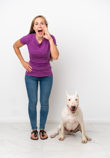 Young English woman with her dog isolated on white background shouting with mouth wide open