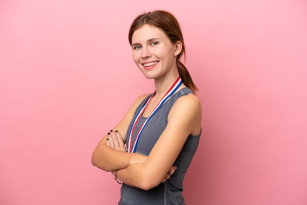 Young English woman with medals isolated on pink background with arms crossed and looking forward