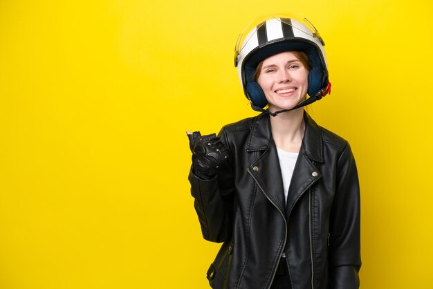 Young English woman with a motorcycle helmet isolated on yellow background pointing to the side to present a product