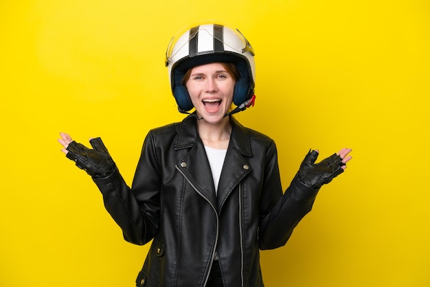 Young english woman with a motorcycle helmet isolated on yellow background with shocked facial expression