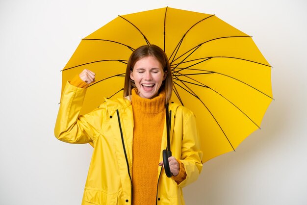 Молодая англичанка в непромокаемом пальто и зонтике на белом фоне делает сильный жест
