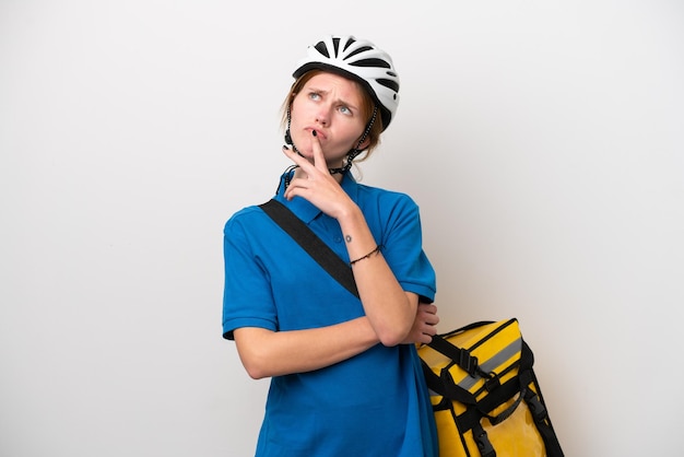 Young English woman with thermal backpack isolated on white background having doubts while looking up