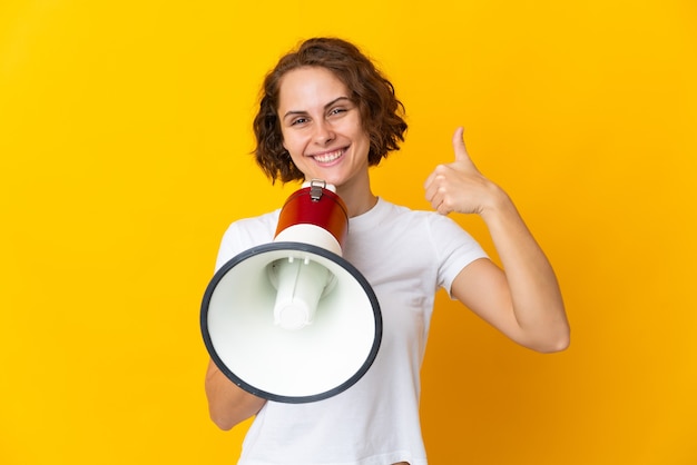 Young English woman on yellow holding a megaphone with thumb up