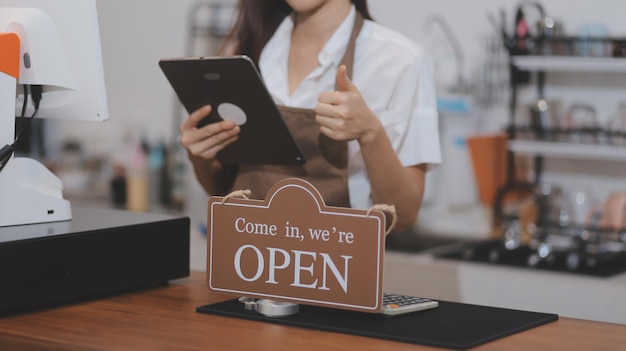 Young entrepreneur holding open sign on glass door at cafe