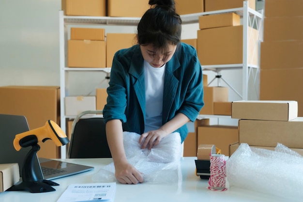 Photo young entrepreneur packing product in mailing box for shipping