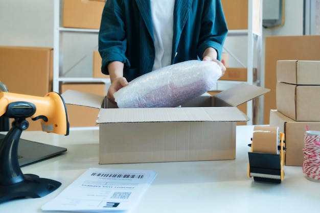 Young entrepreneur packing product in mailing box for shipping