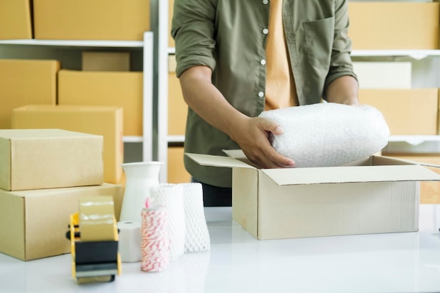 Young entrepreneur packing product in mailing box for shippingxA