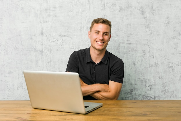 Young entrepreneur working with his laptop on a desk laughing and having fun.