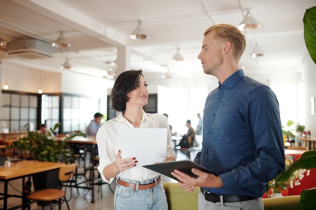 Young entrepreneurs standing in office cafeteria and arranging future meeting