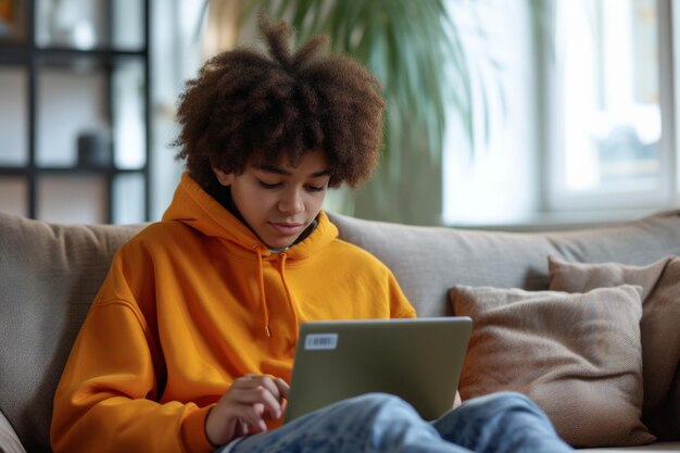 Young ethnic Latin Boy teenager uses laptop and phone at same time to chat with friends and use social networks on Internet sits on sofa with portable computer on lap Digital addiction