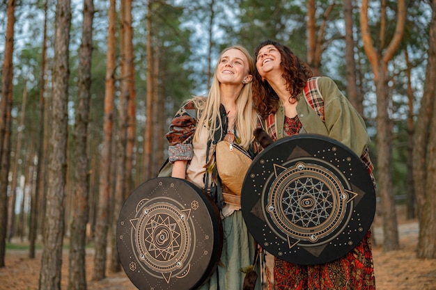 Young ethnic mature shaman female is walking and playing drums meditative music