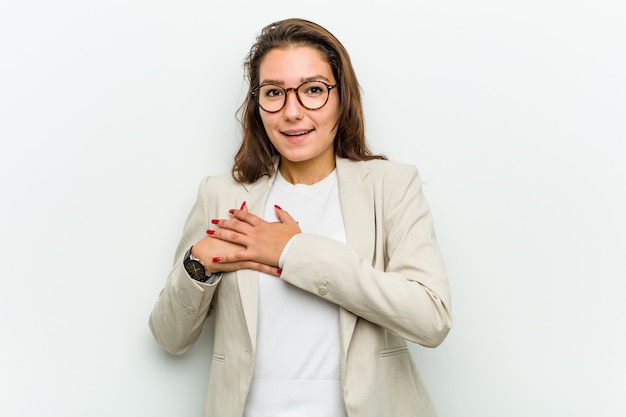 Young european business woman has friendly expression, pressing palm to chest. love concept.