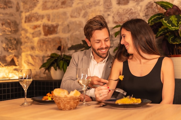 Молодая европейская пара в ресторане, весело обедает вместе с едой, празднует валентинку