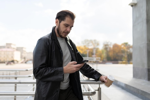 Young european freelancer with a smartphone in his hands checks messages