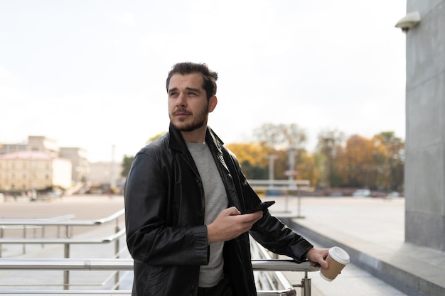 Young european freelancer with a smartphone in his hands at the entrance to the building