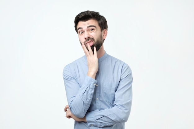 Young european man in blue shirt thinks looks through incredulously