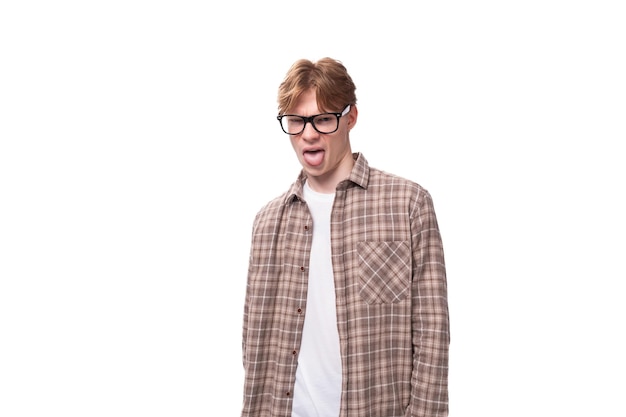 Young european man with golden hair in glasses and a shirt shows a grimace