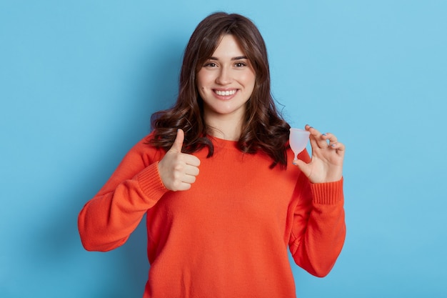 Young European oman holding menstrual cup isolated blue 