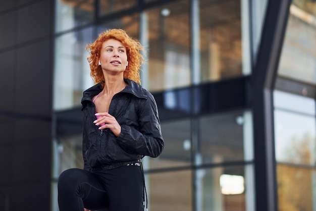 Молодая европейская рыжая женщина в спортивной одежде занимается фитнесом на открытом воздухе