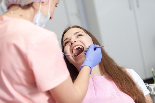 Young European woman being examined by the stomatologist Beauty woman sitting in medical chair while dentist fixing her teeth at dental clinic Dentist examining patient's teeth