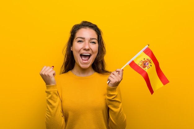 Young european woman holding a spanish flag cheering carefree and excited