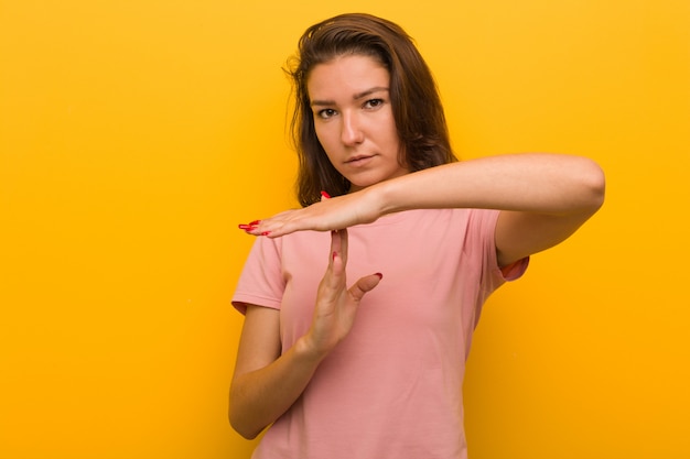 Young european woman isolated over yellow background showing a timeout gesture.