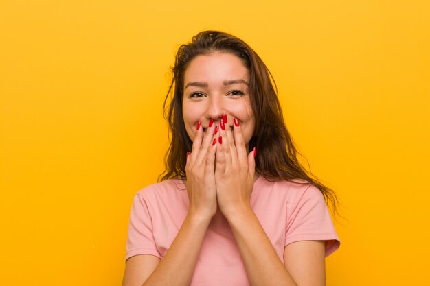 Young european woman isolated over yellow laughing about something, covering mouth with hands.