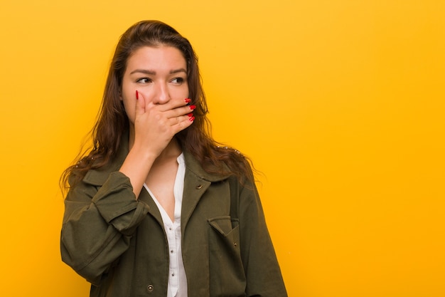 Photo young european woman isolated on yellow thoughtful looking to a copy space coning her mouth with hand.