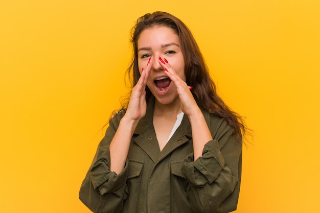 Young european woman isolated over yellow wall shouting excited to front.