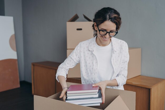 Young european woman packing container and puts textbooks into Relocation and entering to college