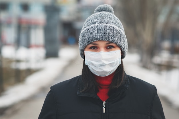 街の通りに保護の使い捨て医療マスクの若いヨーロッパの女性。危険な2019-nCoVインフルエンザコロナウイルスの概念保護