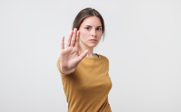 Young european woman standing with outstretched hand showing stop gesture