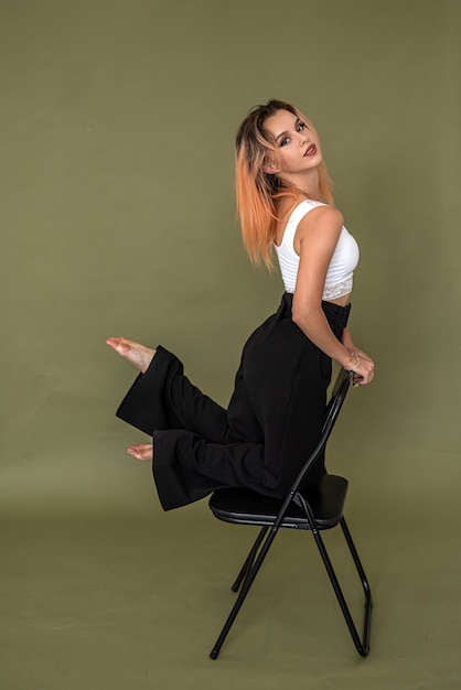 Young european woman in stylish white top and black pants posing in full growth isolated