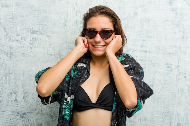 Young european woman wearing bikini covering her ears with her hands.